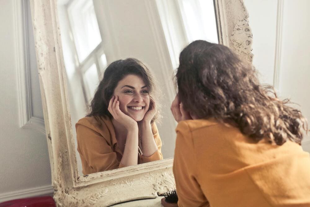 Photo of happy woman looking at herself in the mirror