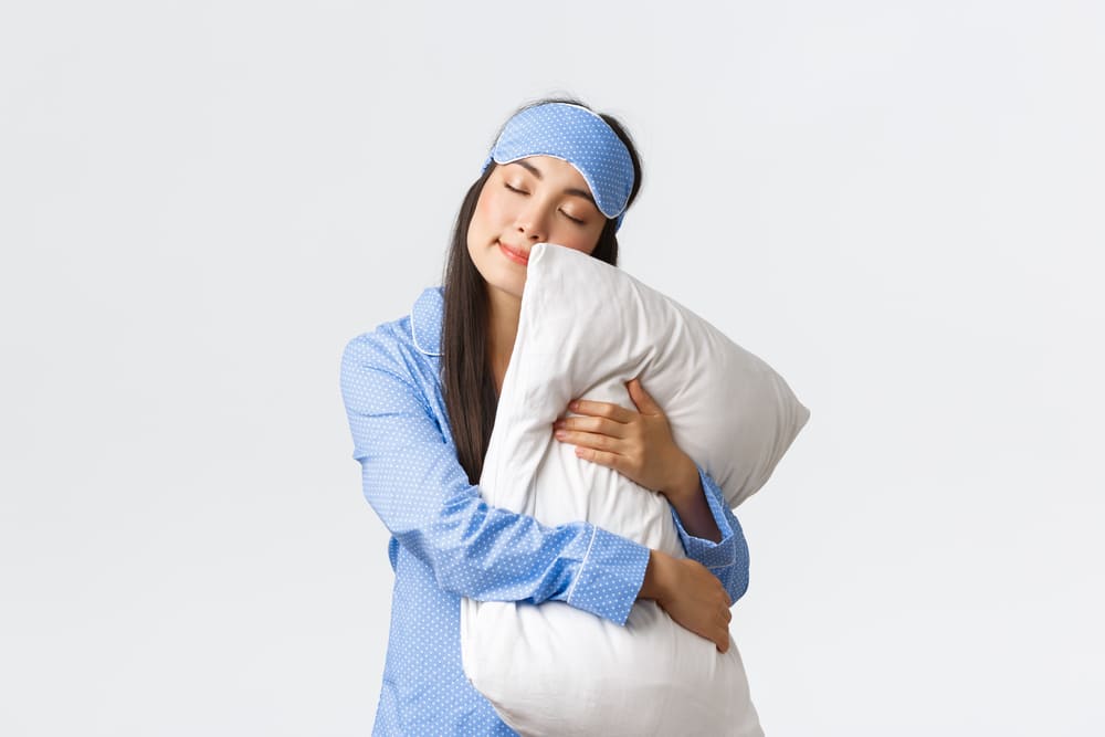 charming-sleeping-asian-girl-eyemask-pyjama-hugging-pillow-lying-it-with-closed-eyes-dreaming-having-night-sleep-posing-white-background-dreamy