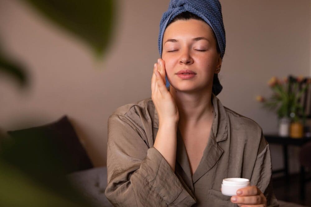 close-up-view-of-fresh-woman-with-cream-on-her-face-at-home-looking-in-the-mirror