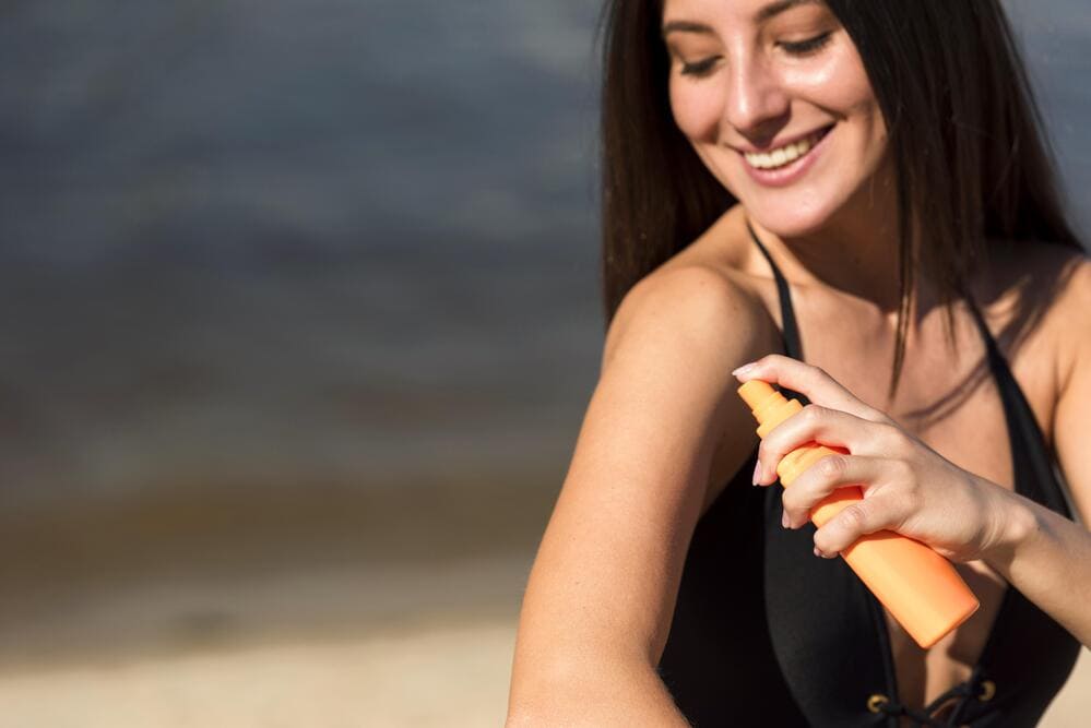 smiley-woman-applying-sunscreen-beach