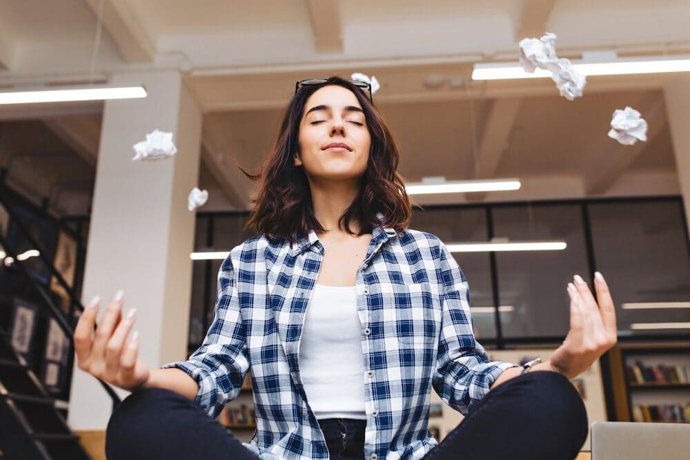 relaxing-time-cheerful-young-brunette-having-meditation-at-desk-in-office-surround-papers-flying-taking-a-break-pause-smart-student-relaxation-great-success-dreaming