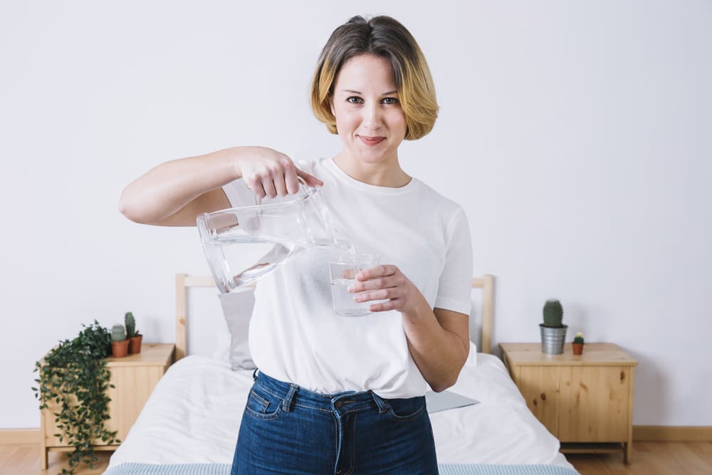 woman-pouring-water-looking-camera-and-happy-for-know-the-Benefits-of-Water-for-Your-Skin