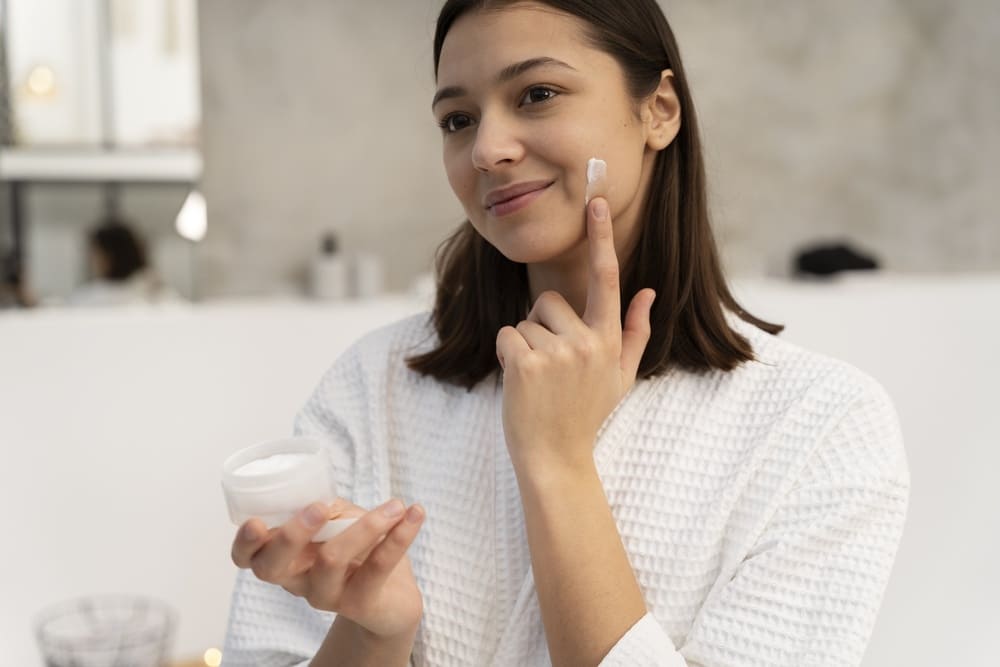 young-woman-applying-moisturizer-her-face-before-taking-bath