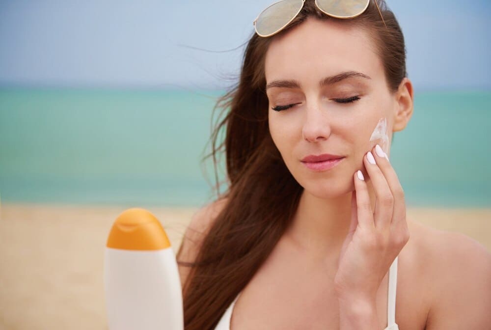 young-and-beautiful-woman-applying-sunscreen-on-the-beach